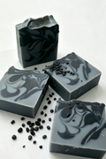 4 soaps with a textured top, black & bluey grey swirl design, surround by charcoal pips