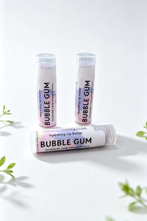 3 lip balm sticks on a white background surrounded by sprigs of green leaves