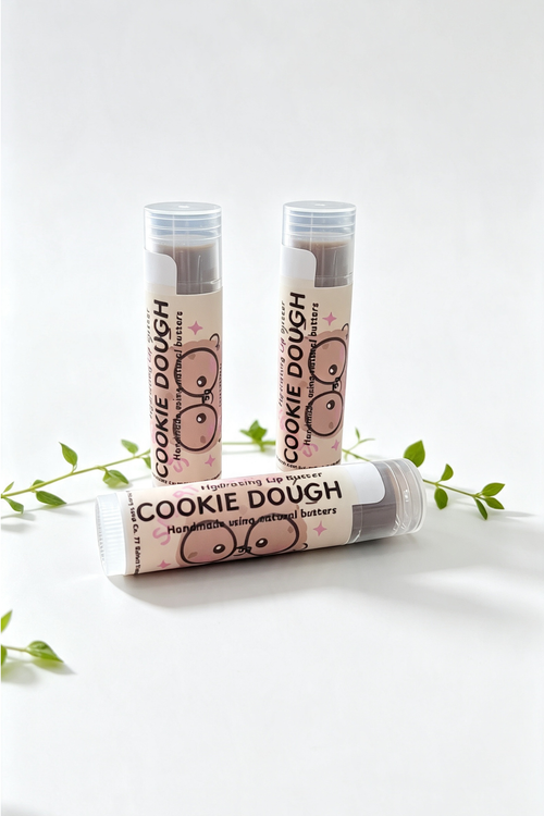 3 lip balm sticks on a white background surrounded by sprigs of green leaves