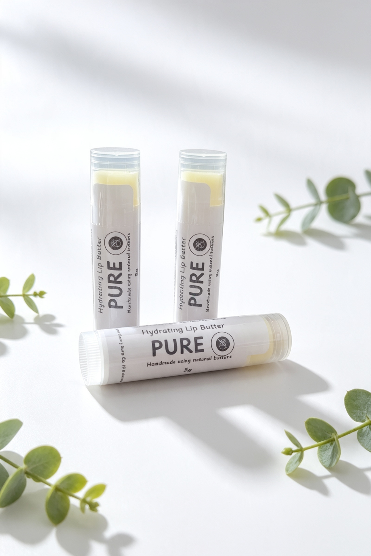 3 lip balm sticks on a white background with sprigs of leaves